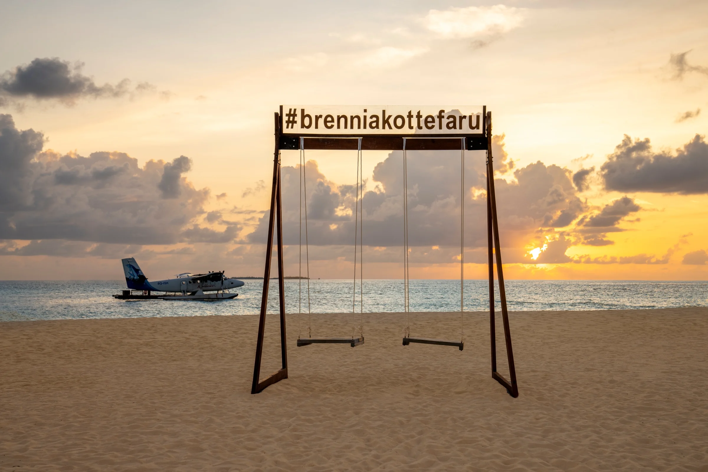 Beach swing at sunset with a seaplane, Brennia Kottefaru