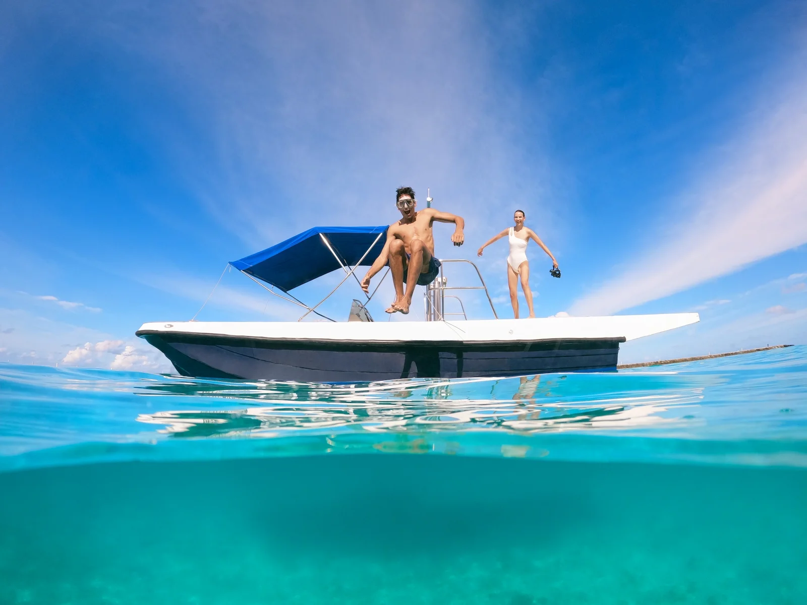Couple jumping off a boat into the ocean, Centara Ras Fushi