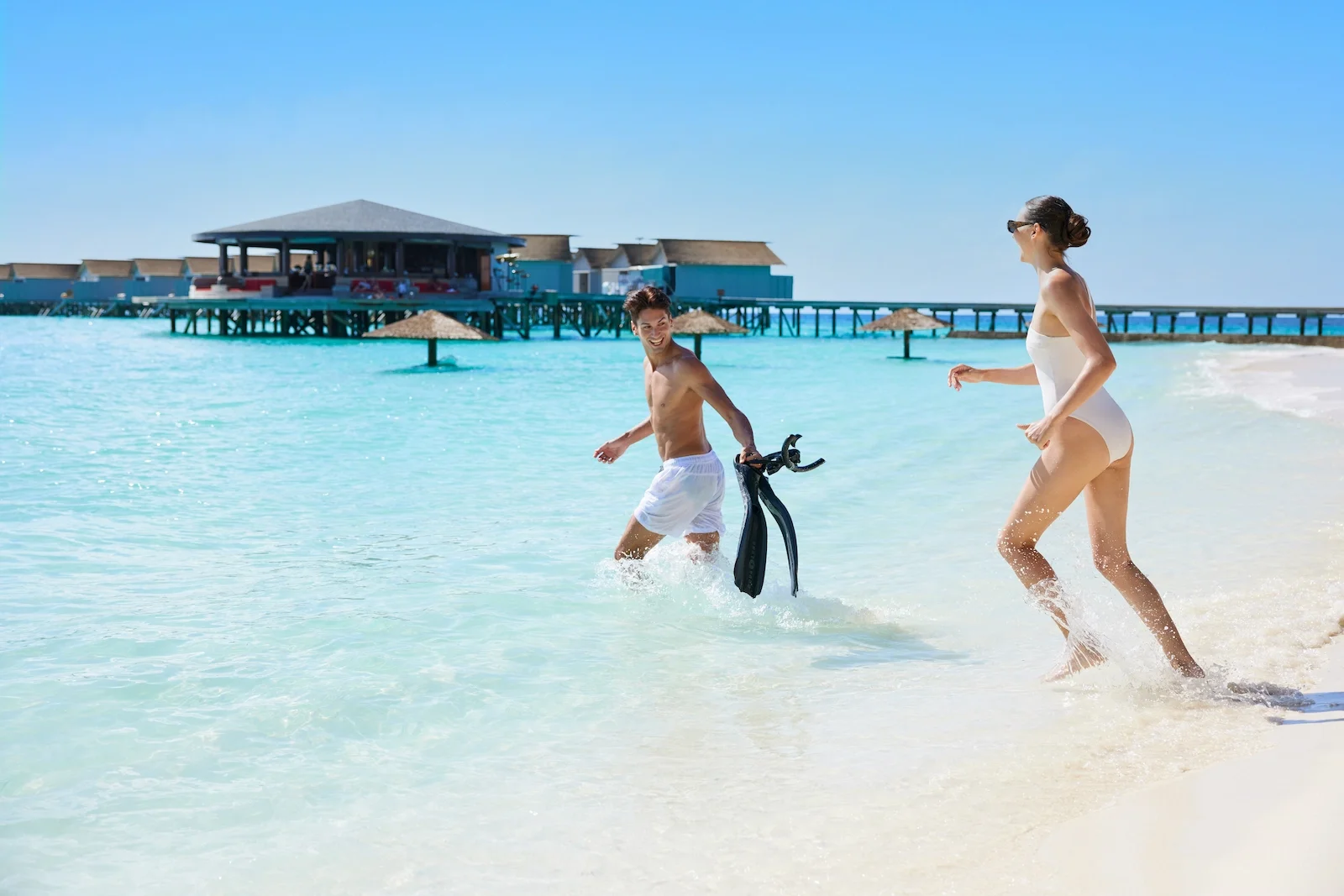 Couple running into the lagoon with snorkel fins, Centara Ras Fushi