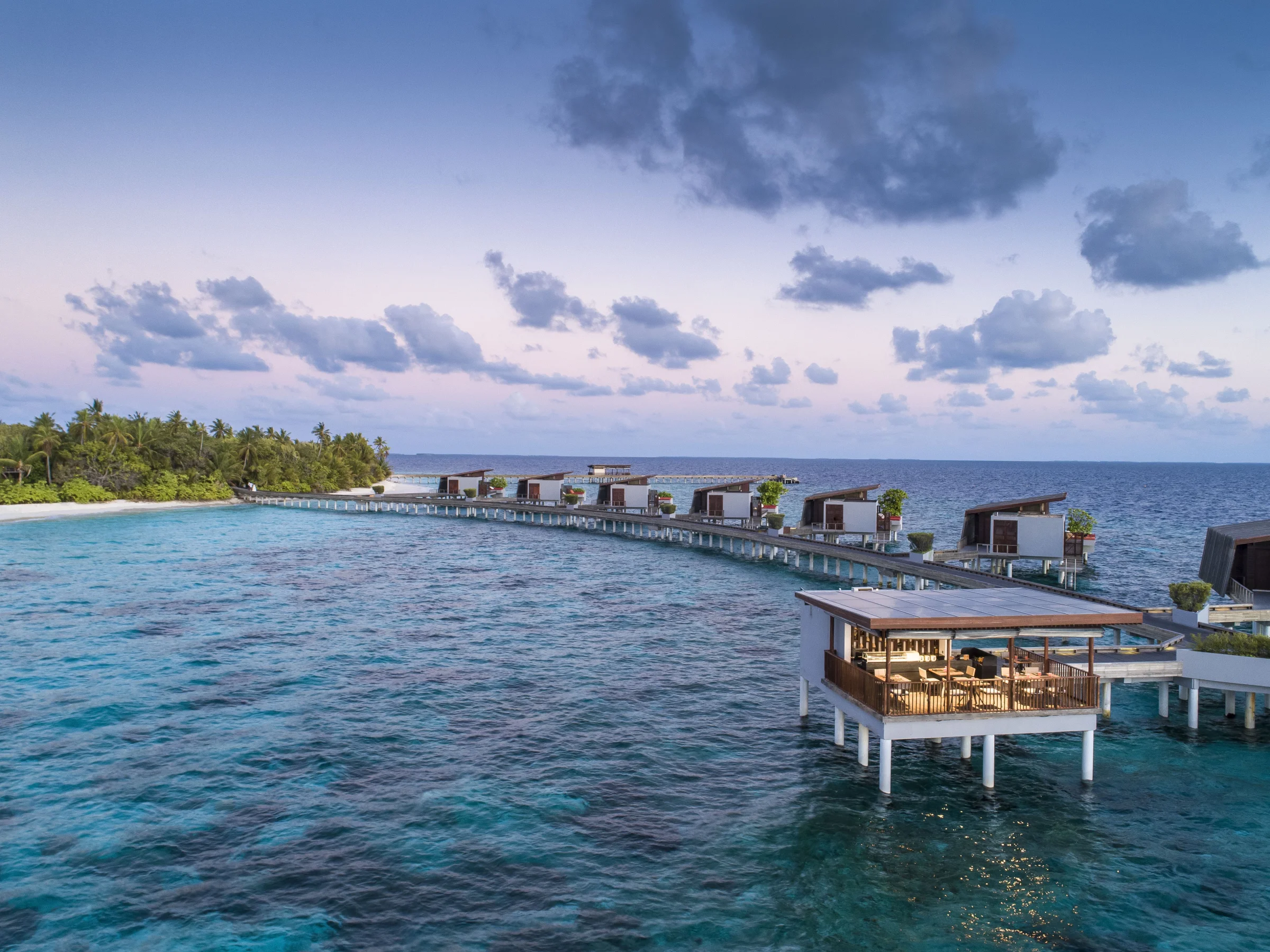Overwater pavilion and water villas at dusk, Park Hyatt Maldives Hadahaa